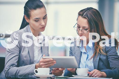 Image Of Two Confident Businesswomen Working With Touchpad In Office